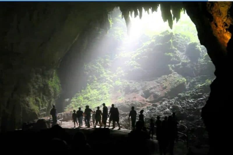 Outdoor cave entrance silhouette with hikers exploring interior