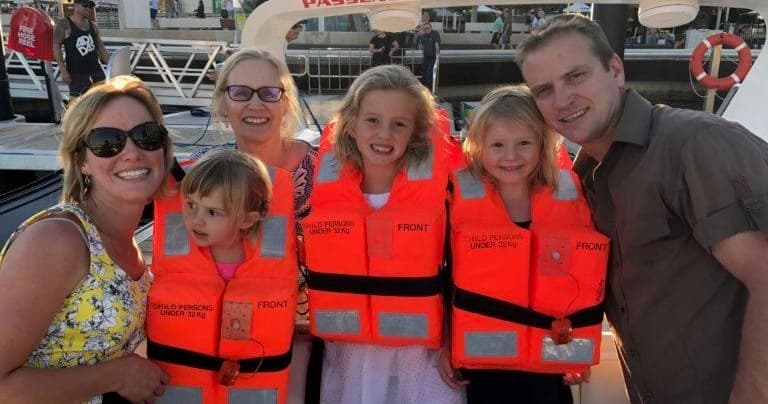Family wearing life jackets aboard charter boat near marina