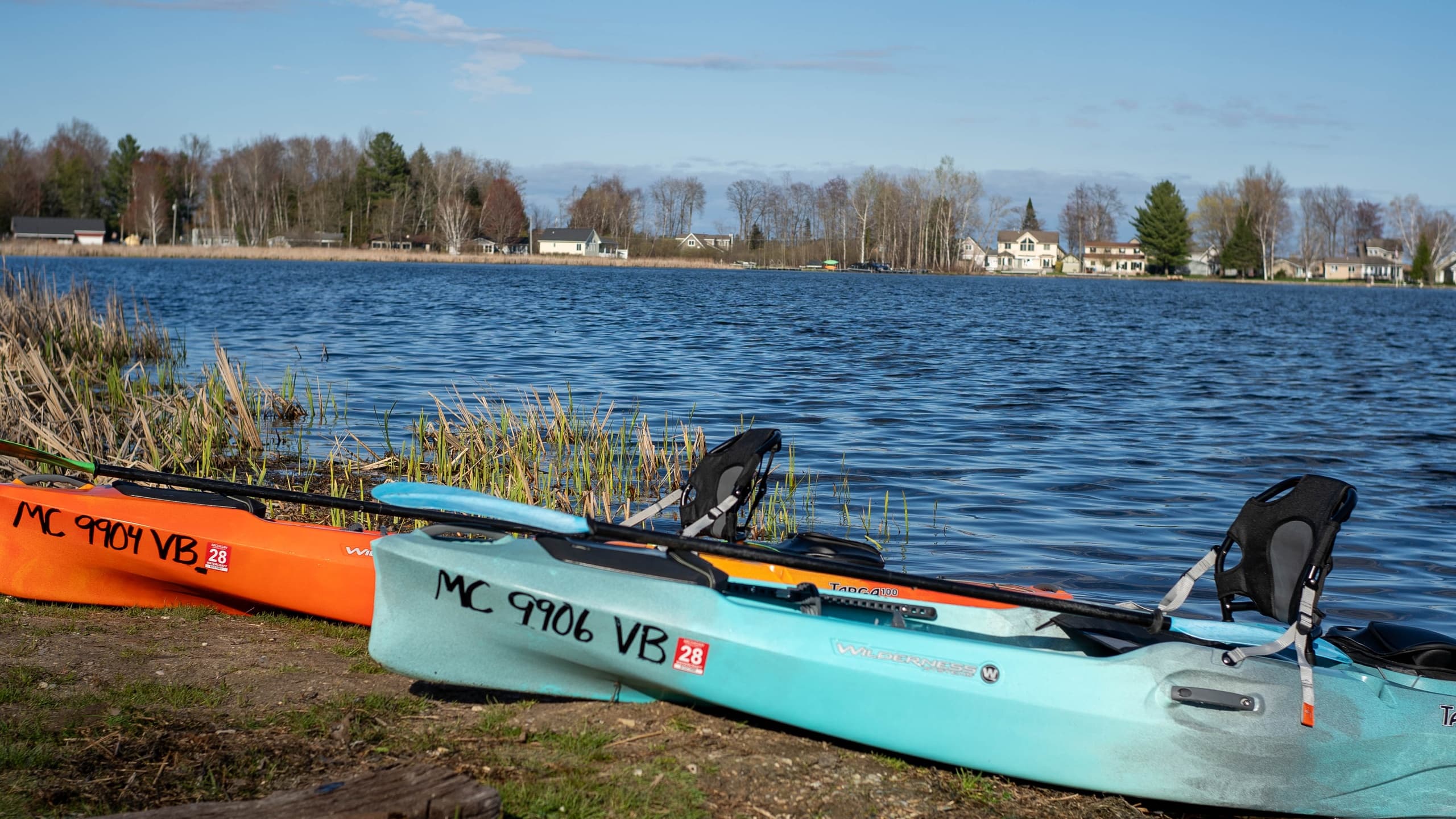Two kayaks pulled ashore by a lakeside, ready for launch