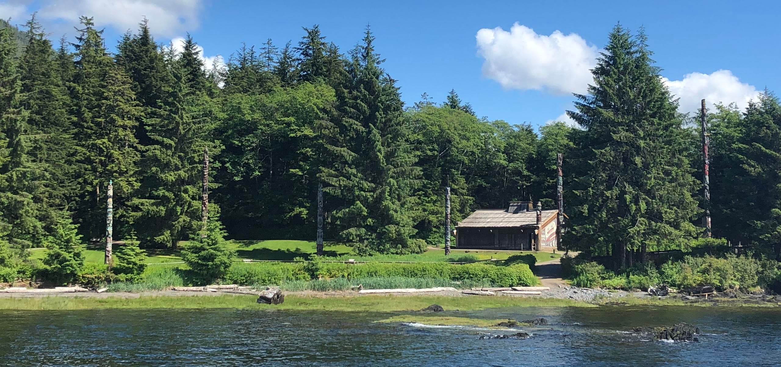 Coastal cabin and evergreen shoreline along calm Alaska bay
