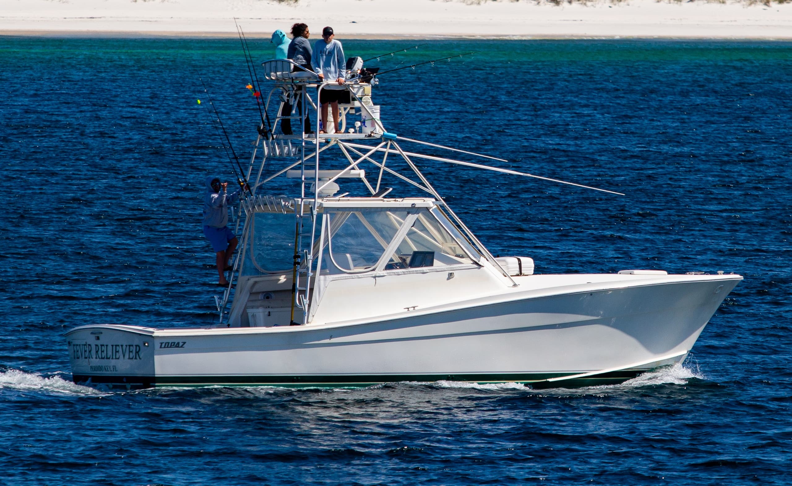 Tuna tower sportfishing boat cruising near sandy shoreline