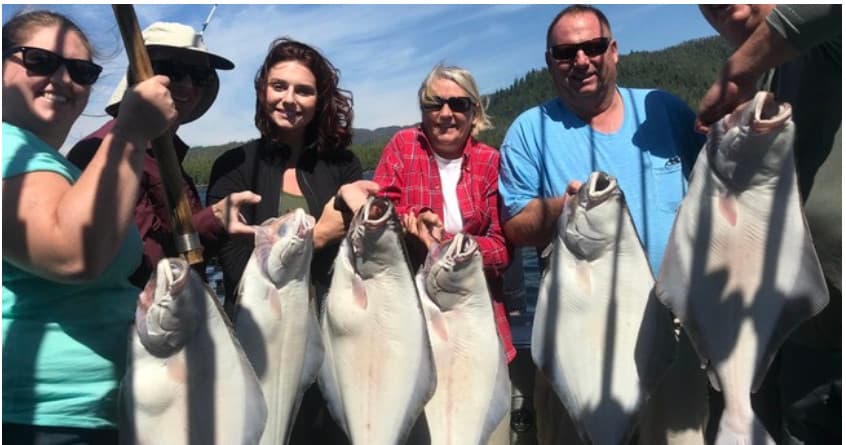 Anglers posing with halibut catch on Alaska fishing charter