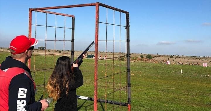 Instructor guiding shooter in framed station on grassy range