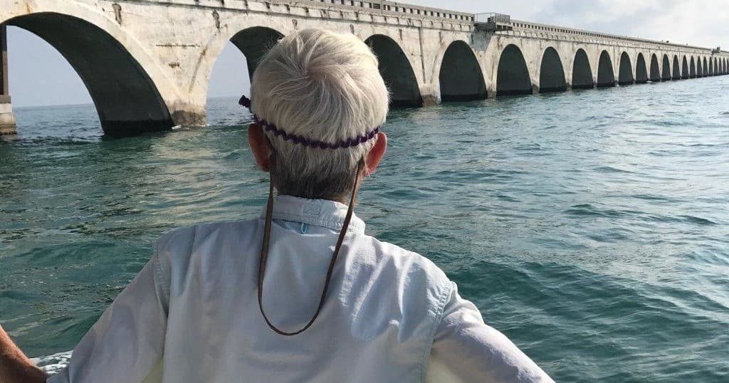 Angler viewing coastal ocean under long arched bridge skyline