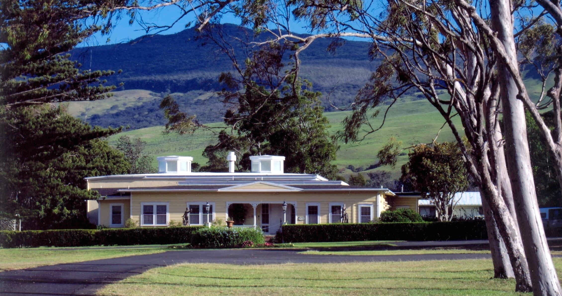 Ranch homestead on grassy pasture with rolling hills backdrop