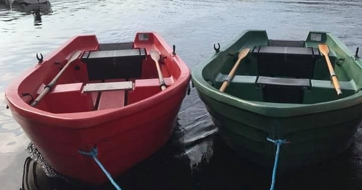 Paired rowboats tied at pier on tranquil lakeside water
