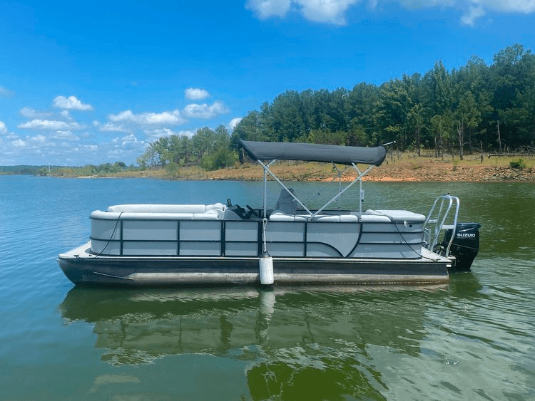 Family pontoon boat cruising along tranquil lake shoreline
