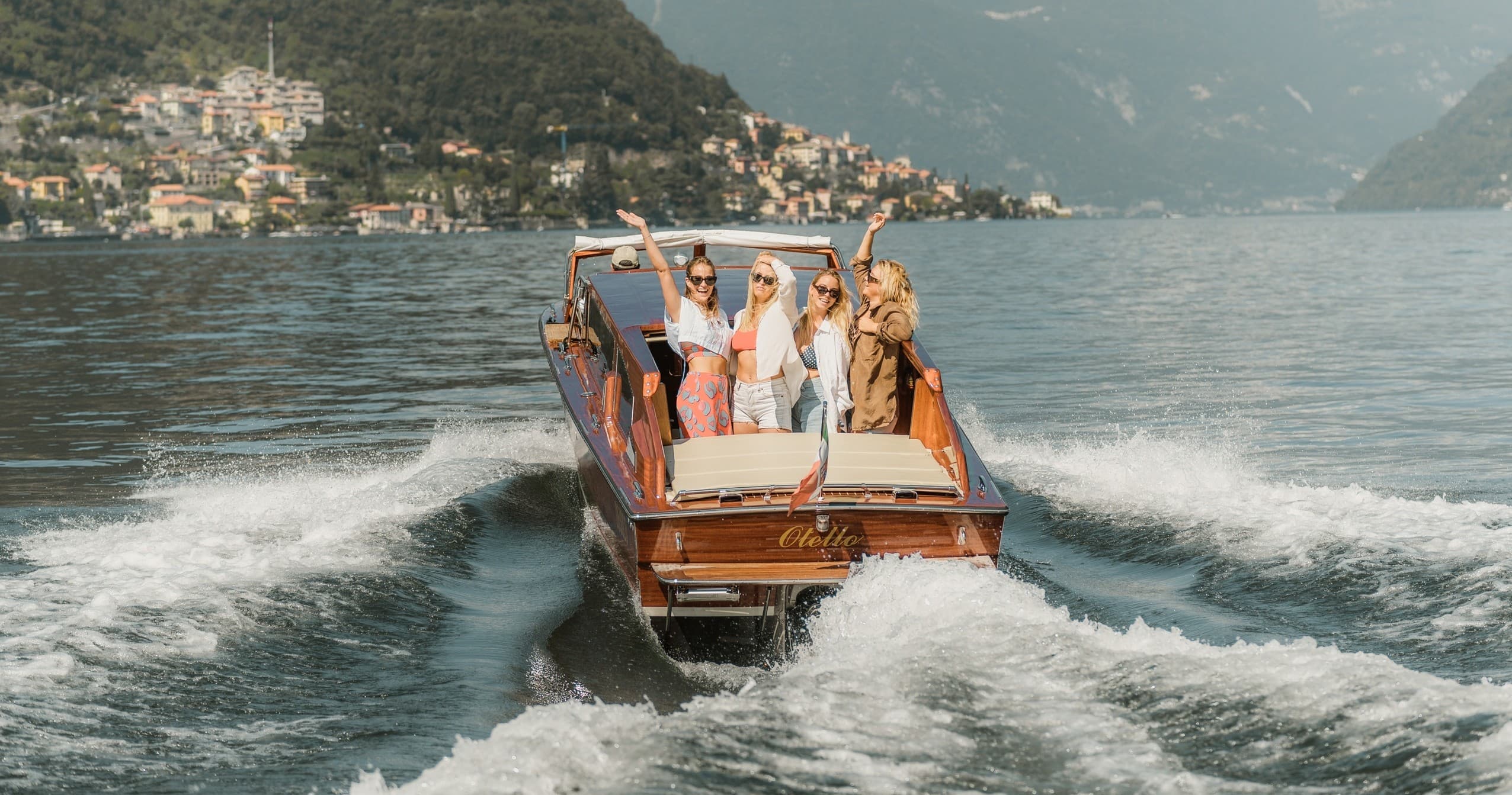 Vintage wooden launch speeding away, passengers enjoying lake tour