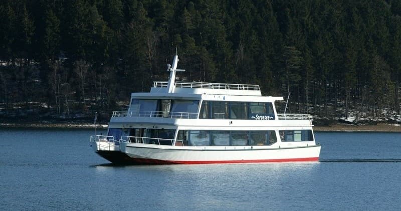Scenic passenger ferry cruising a forested lake shoreline