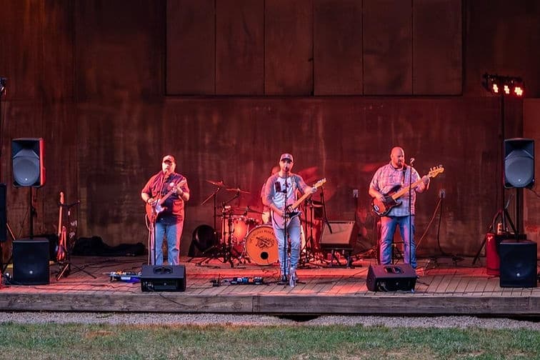 Live band performing on wooden stage at outdoor event