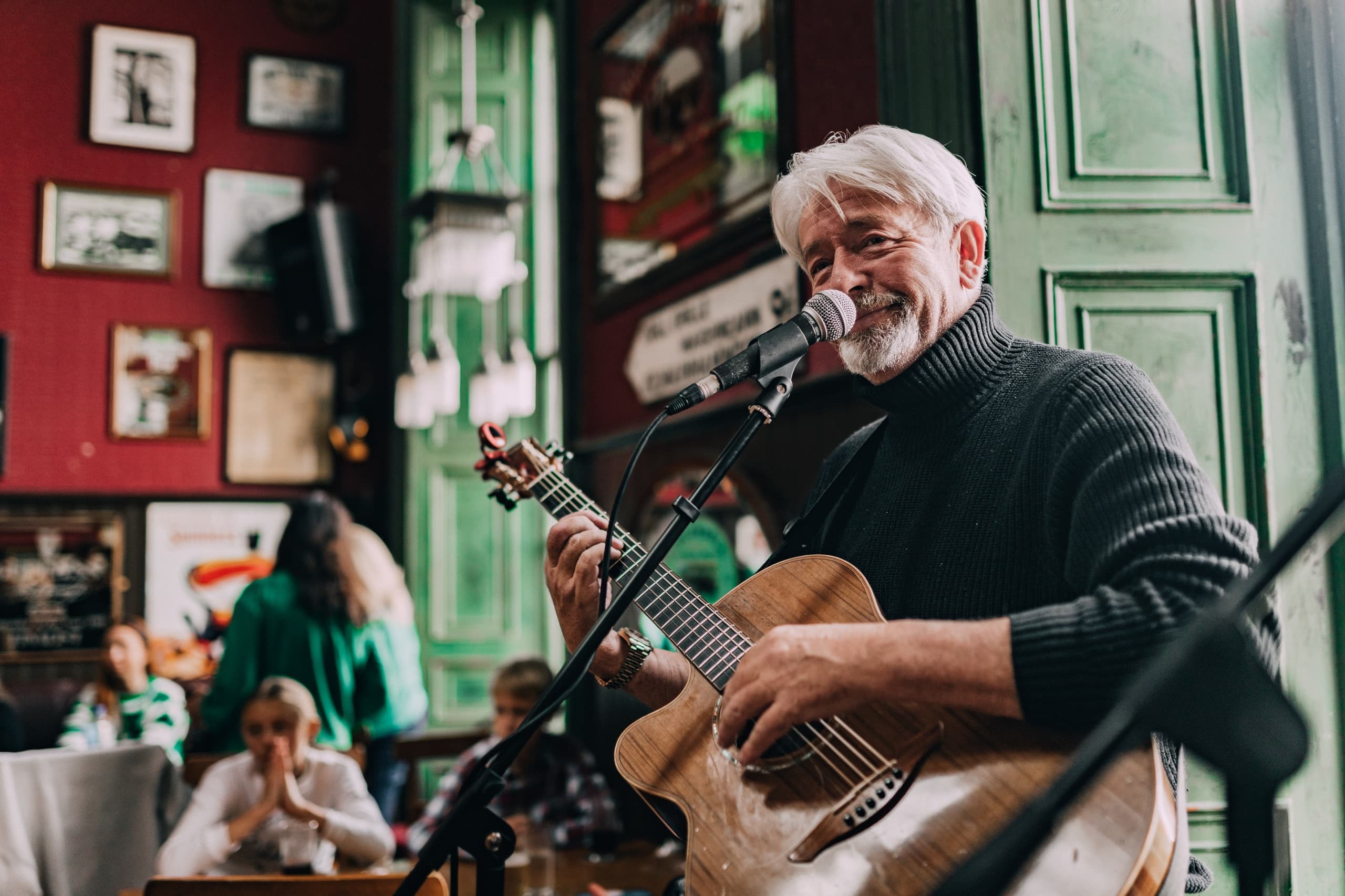 Older guitarist performing live in cozy Irish pub setting