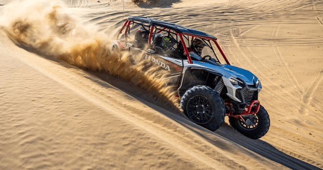 Dune buggy racing across sandy desert dunes kicking up sand