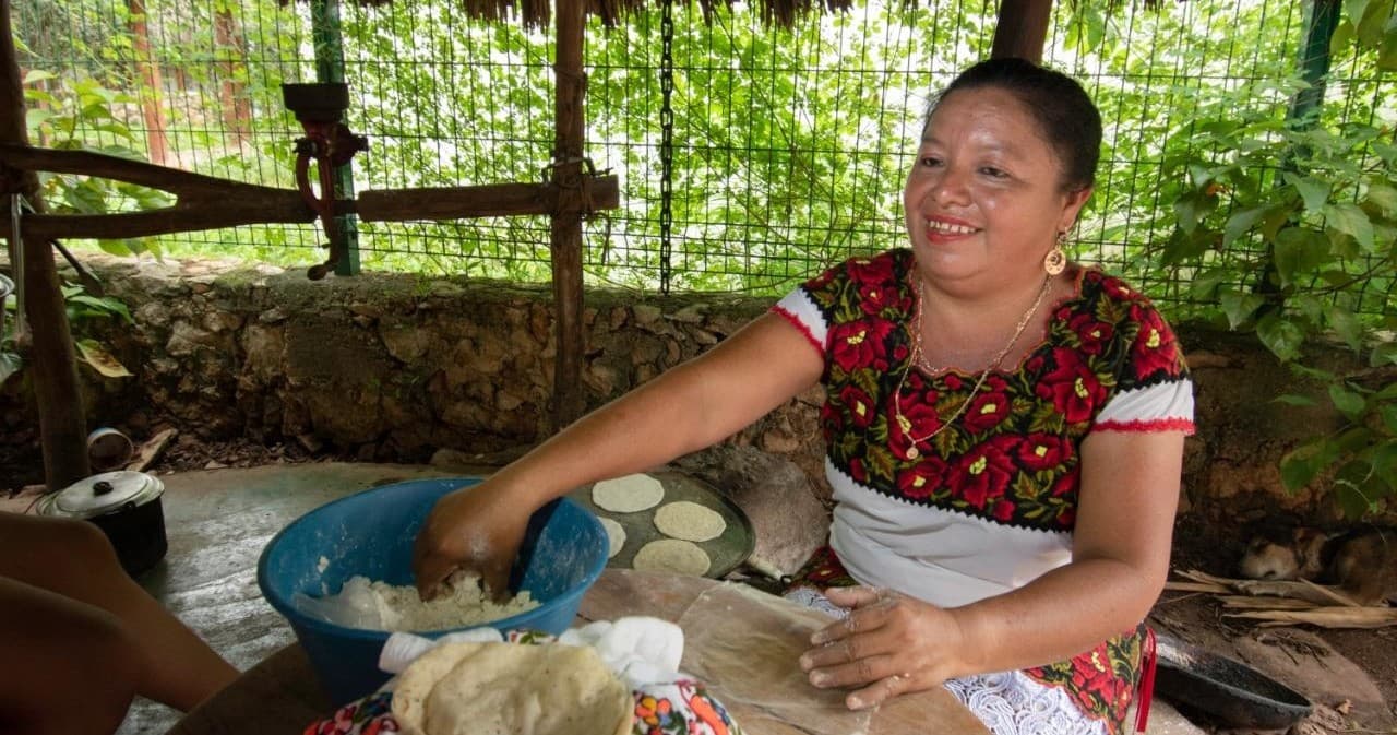 Mayan woman hand-pressing masa outdoors for fresh tortillas
