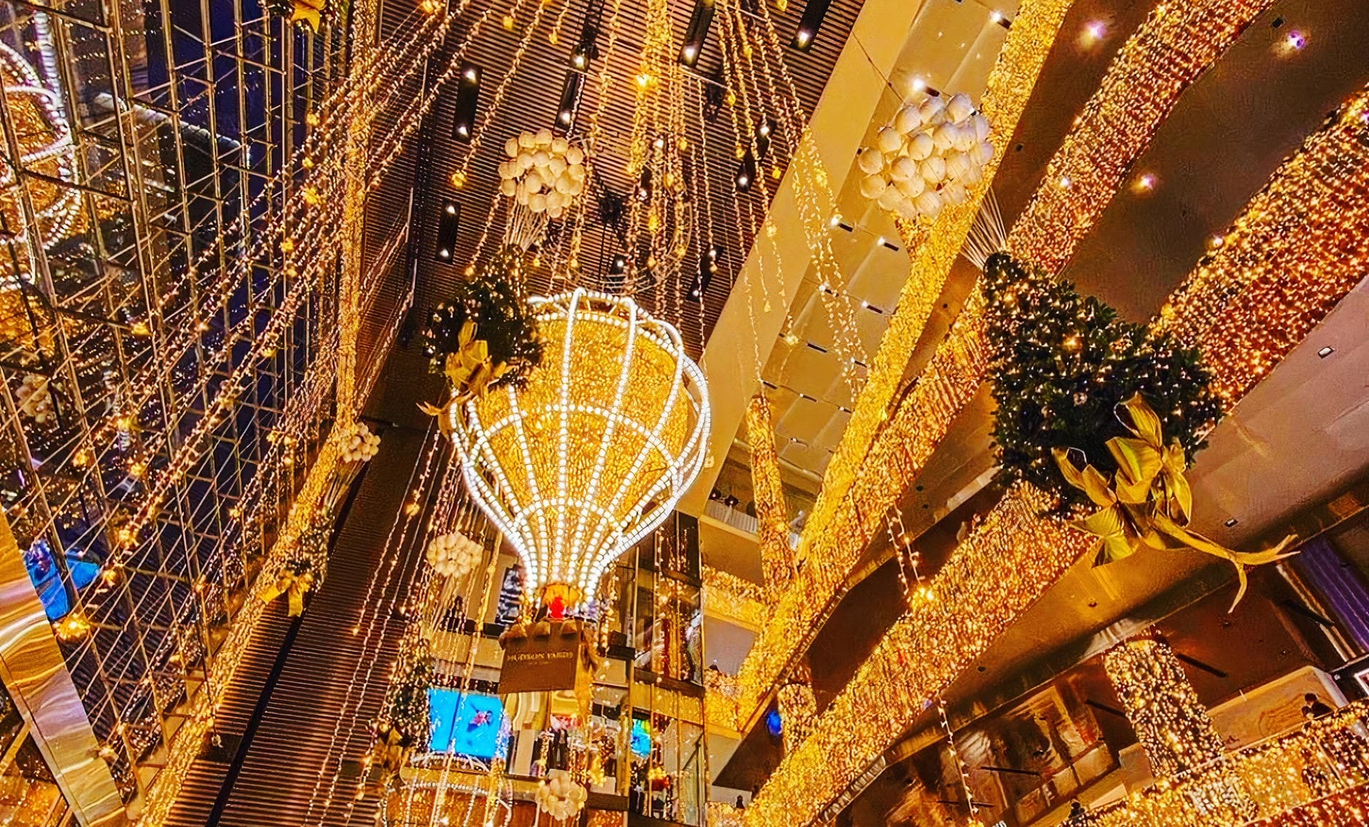 Indoor shopping atrium lit with cascading holiday lights and chandeliers