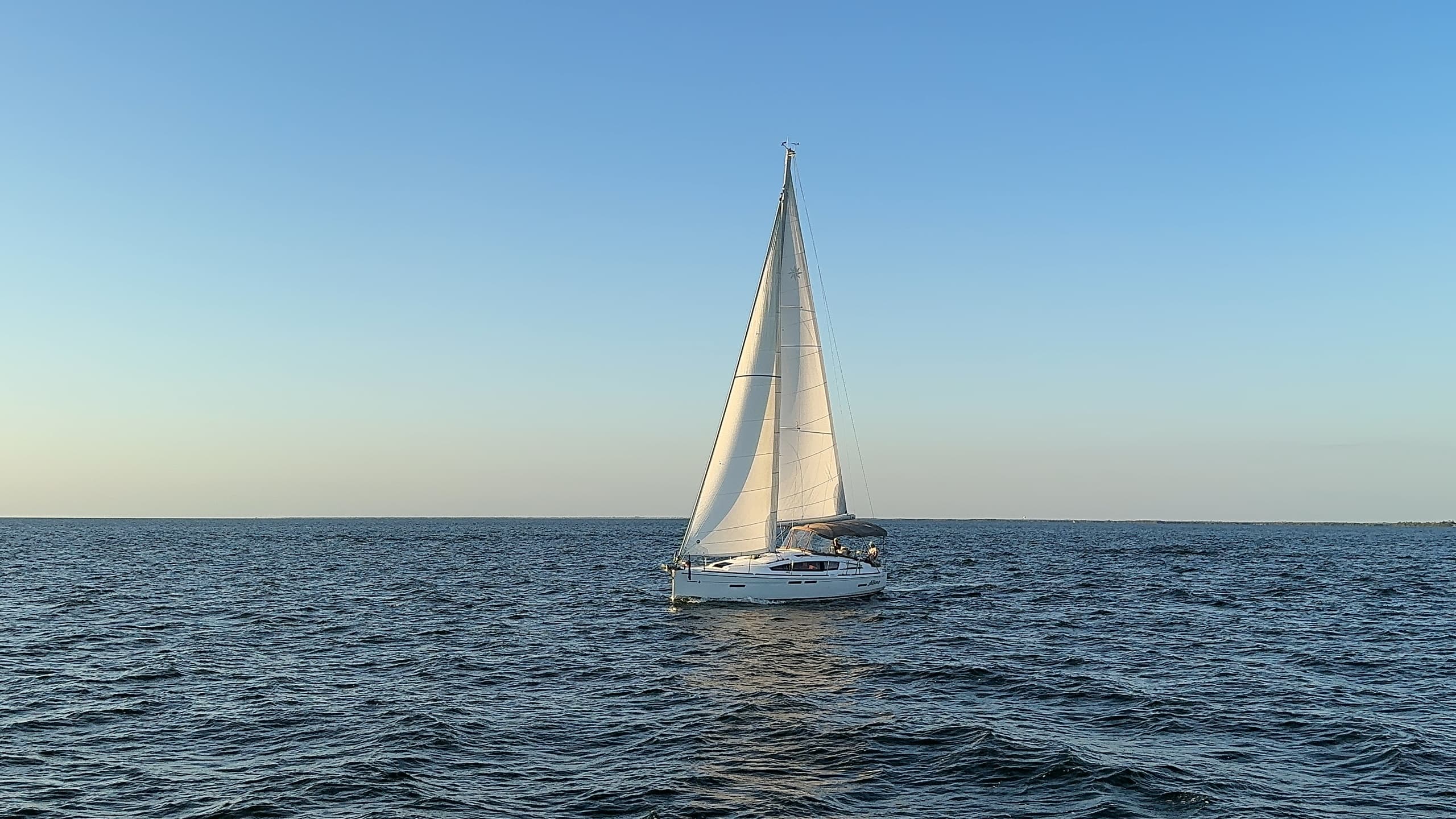 Sailboat cruising on open water with clear horizon