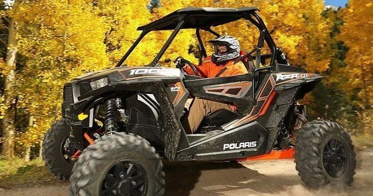Polaris RZR side-by-side driving through autumn forest trail