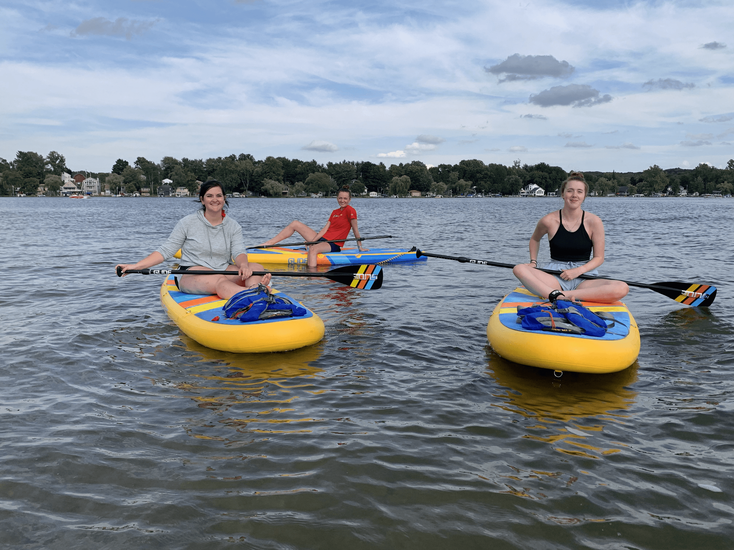 Group paddleboarding on calm lake with inflatable boards