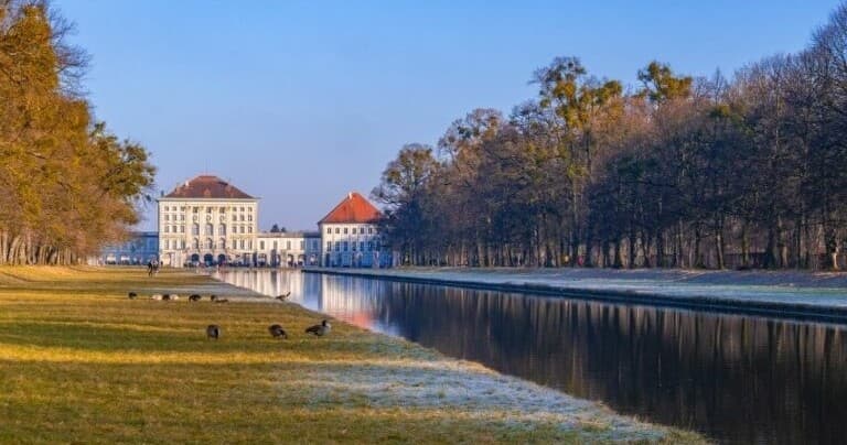 Riverside palace and tree-lined canal, tranquil park stroll