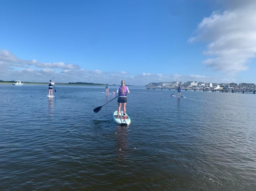 Solo paddleboarder on serene bay under blue summer sky