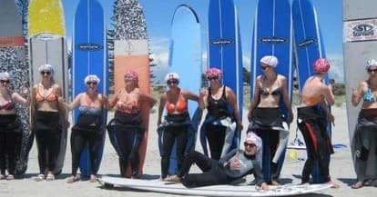 Surf class lineup with instructors and colorful boards on sand