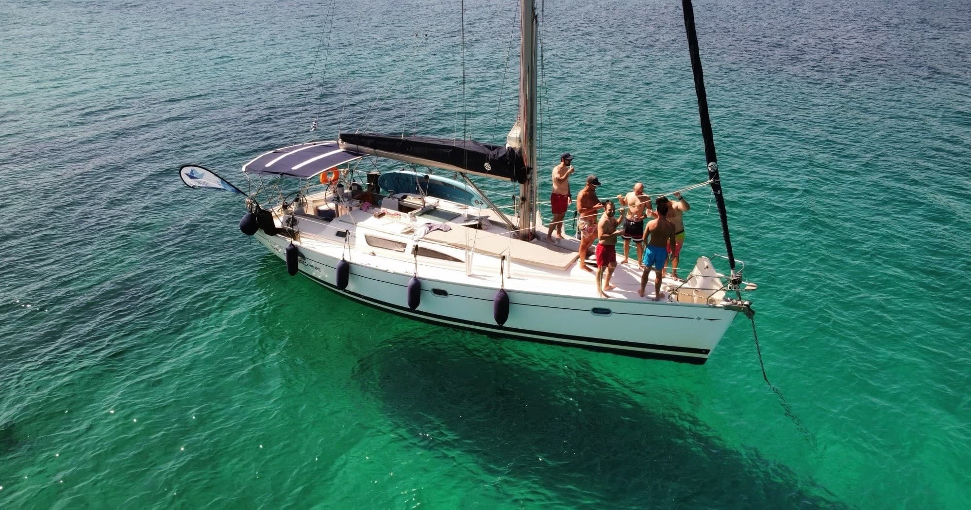 Aerial sailboat cruising clear turquoise coastal waters with guests