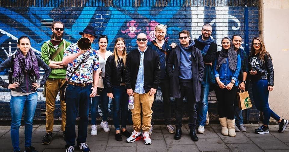 Tour group posing before vibrant graffiti mural on city street