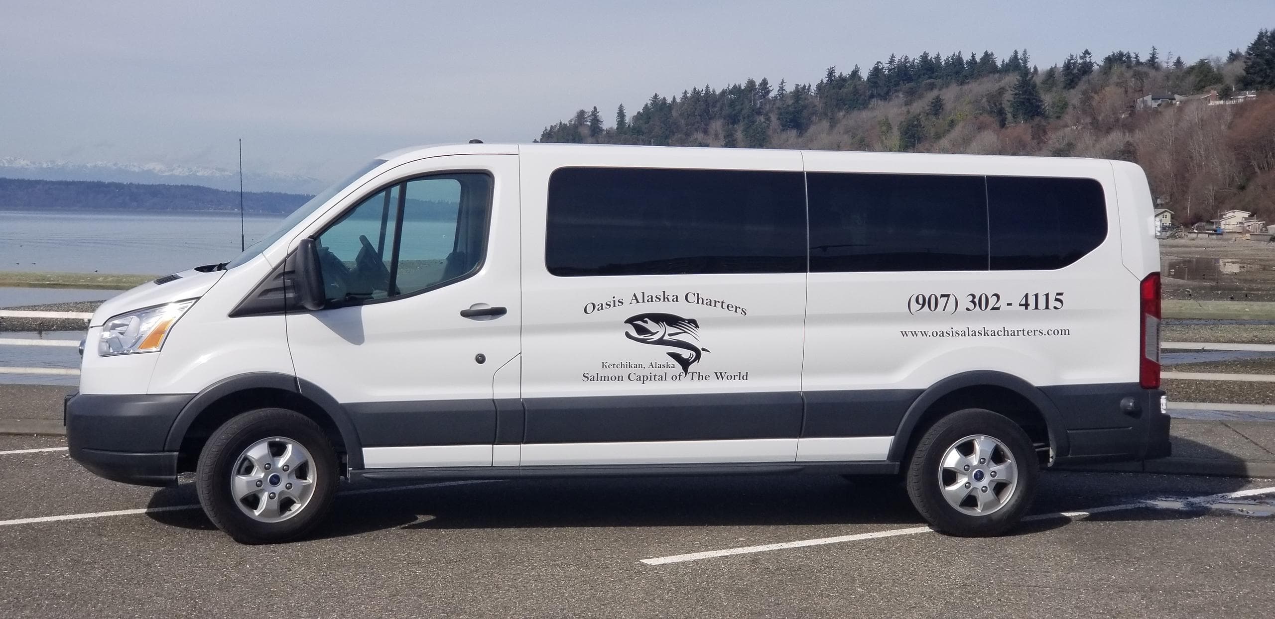 Shuttle van with Oasis Alaska Charters logo parked by waterfront