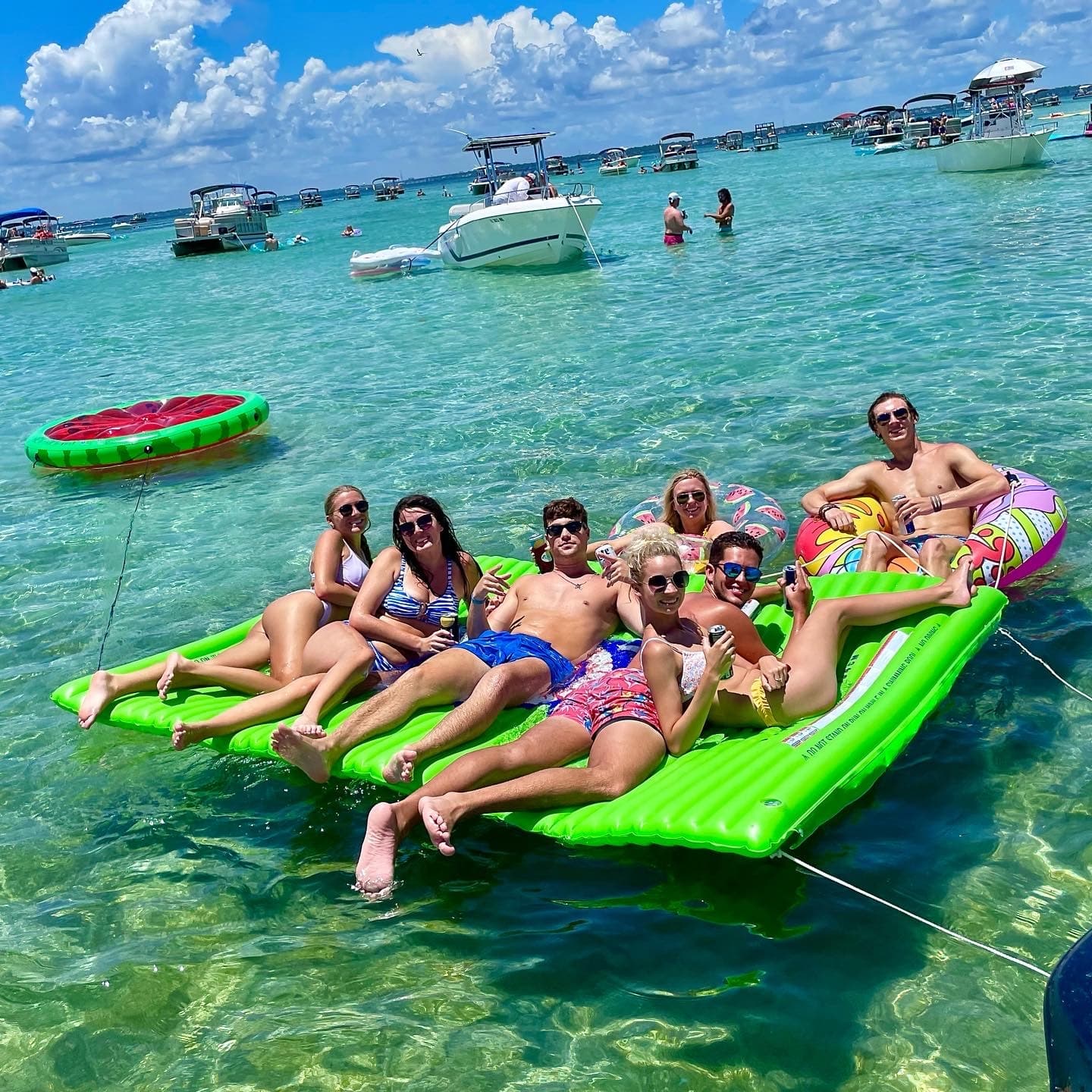 Friends lounging on inflatable raft in shallow turquoise bay