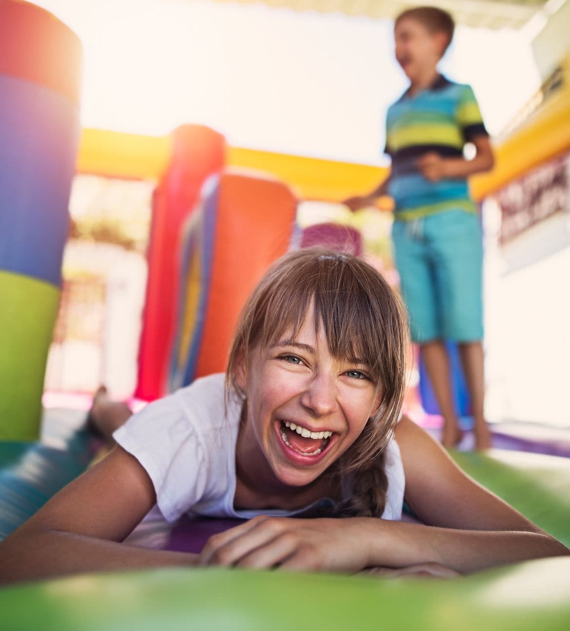 Girl laughing in colorful inflatable jump house at birthday party