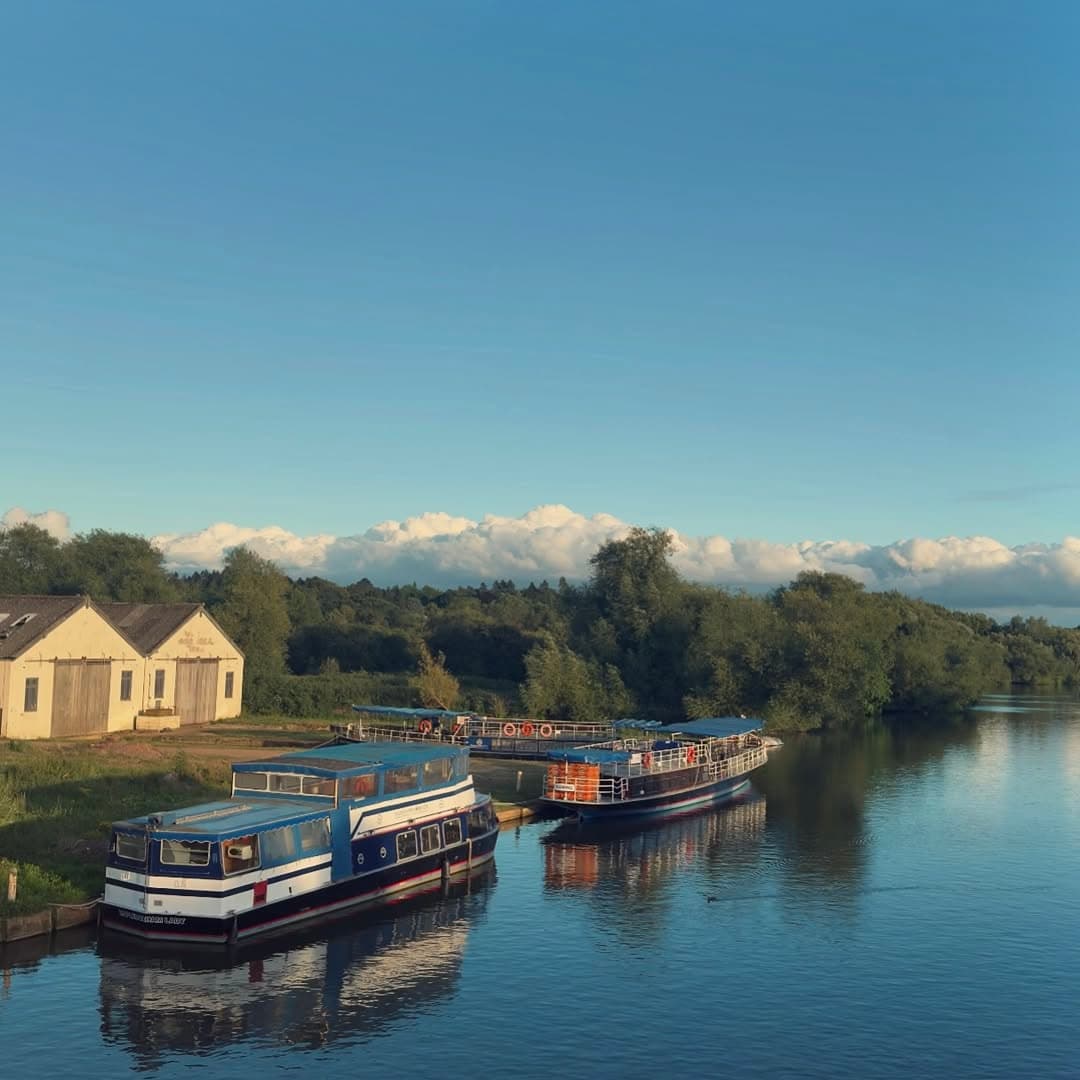 Moored narrowboats on calm river with scenic countryside view
