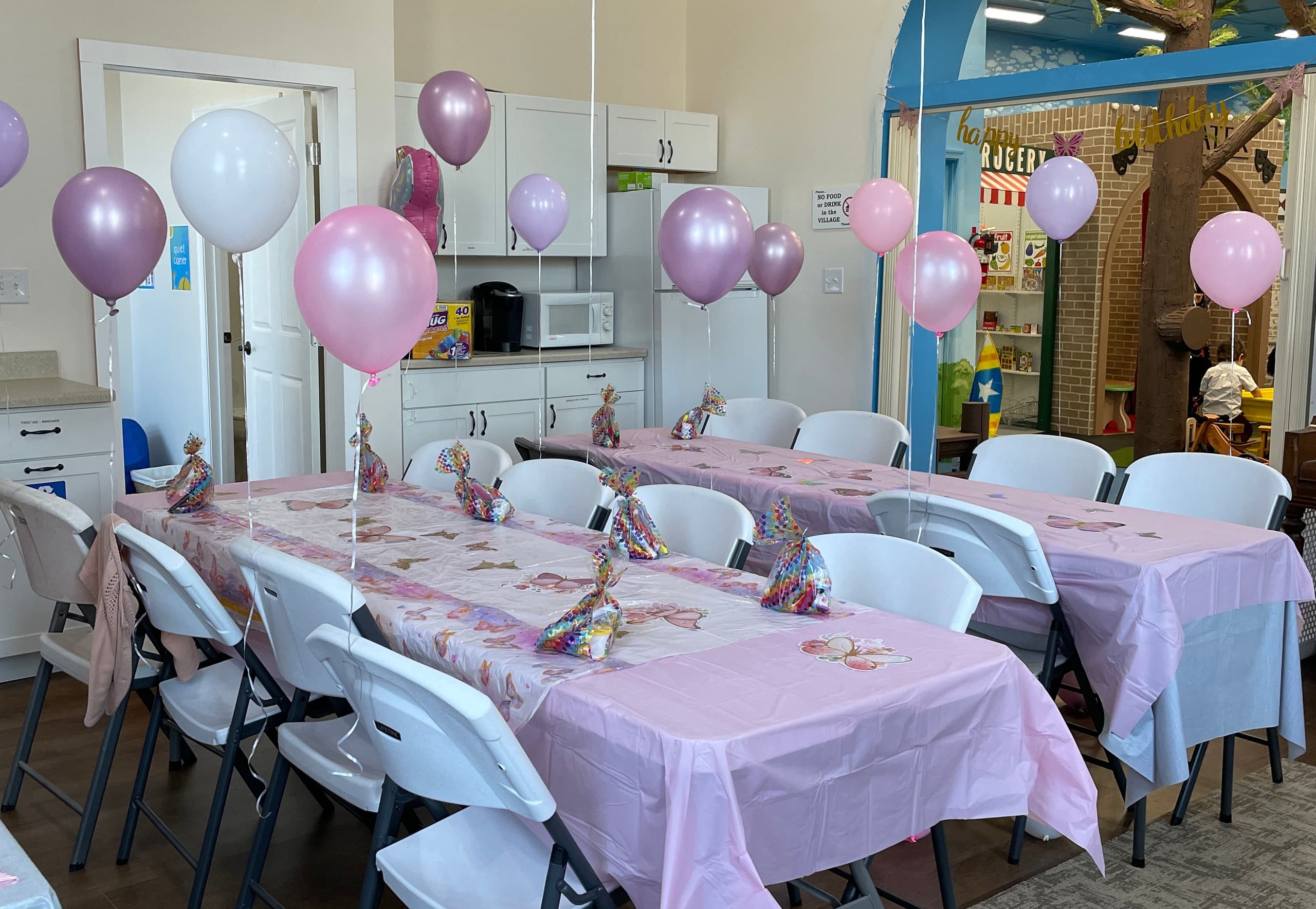 Indoor children's party tables with pink balloons and tableware setup