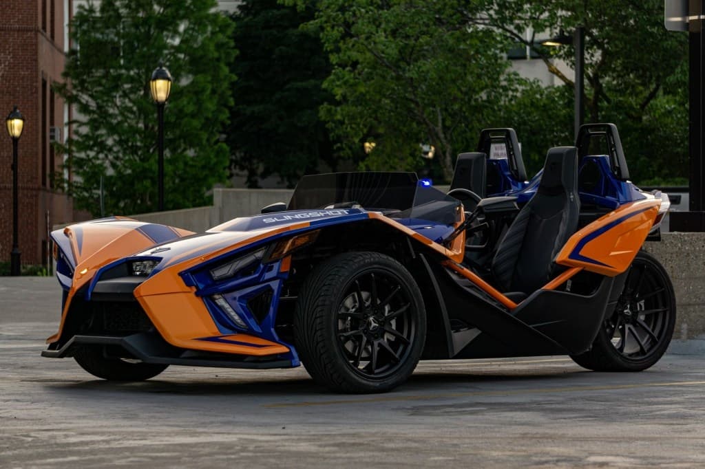 Orange and blue three-wheeler parked on tree-lined street