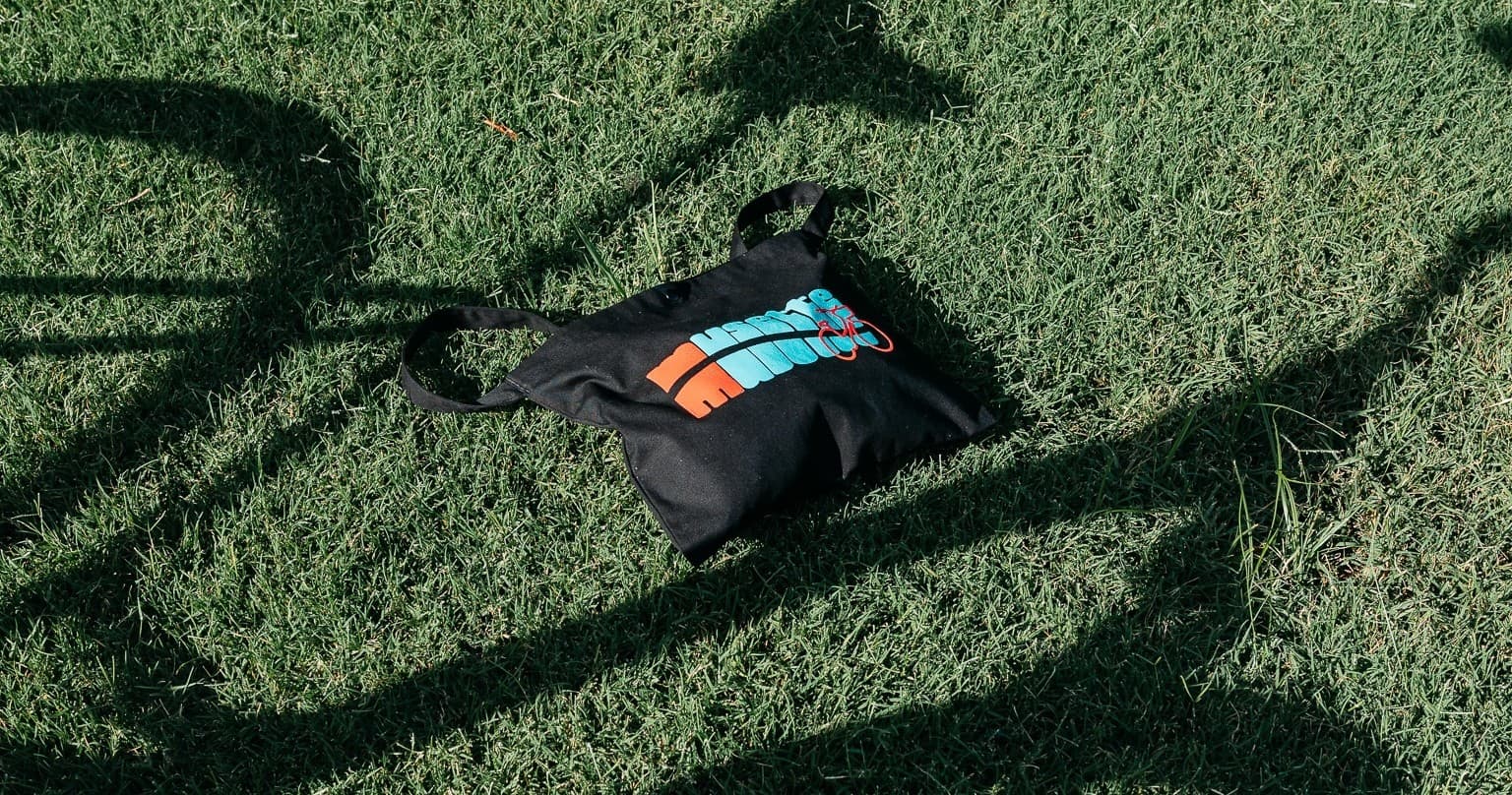 Musette bag on grass beside bicycle shadow in city park
