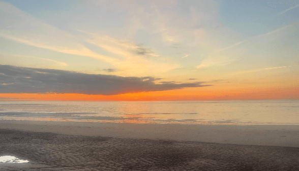Vibrant sunset over sandy beach and calm ocean horizon coastal view