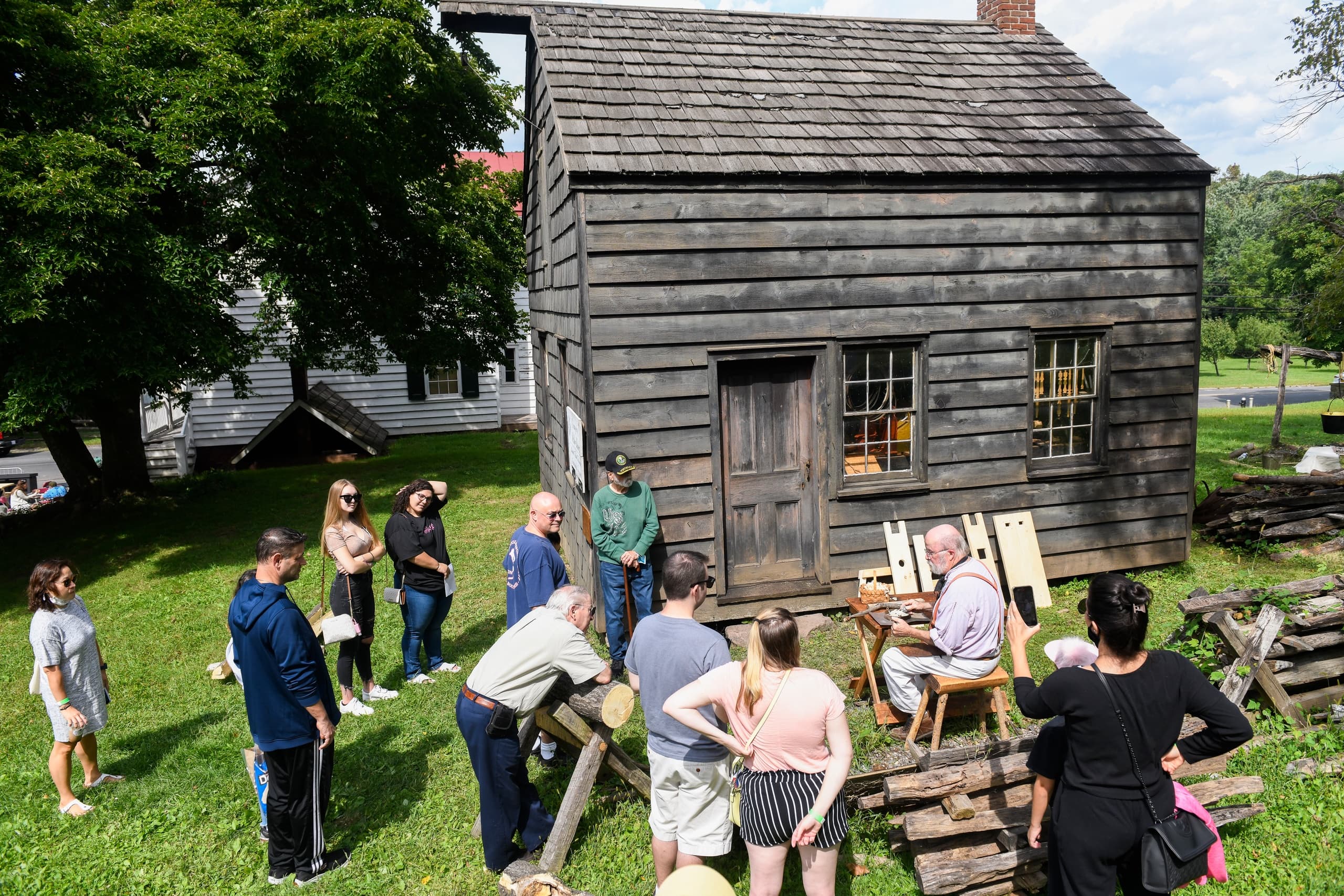 Visitors exploring historic wooden cabin at outdoor Richmond Town