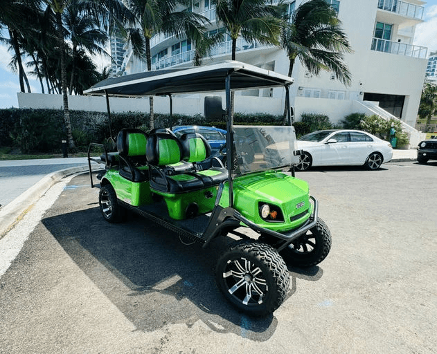 Custom green off-road golf cart parked near palm trees by condos