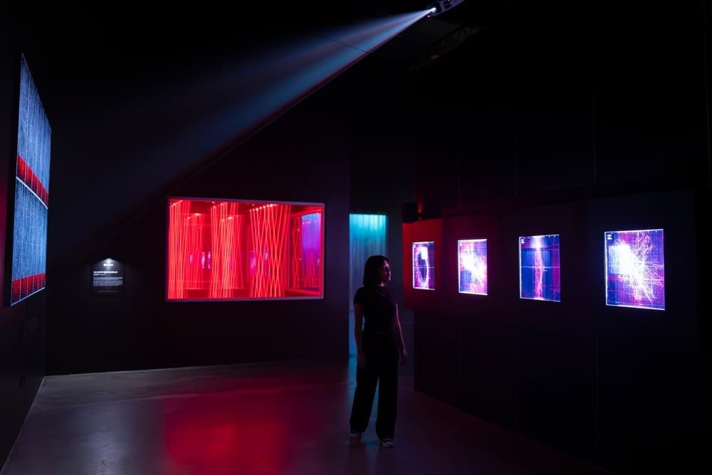 Solo viewer in dark gallery corridor with illuminated digital panels