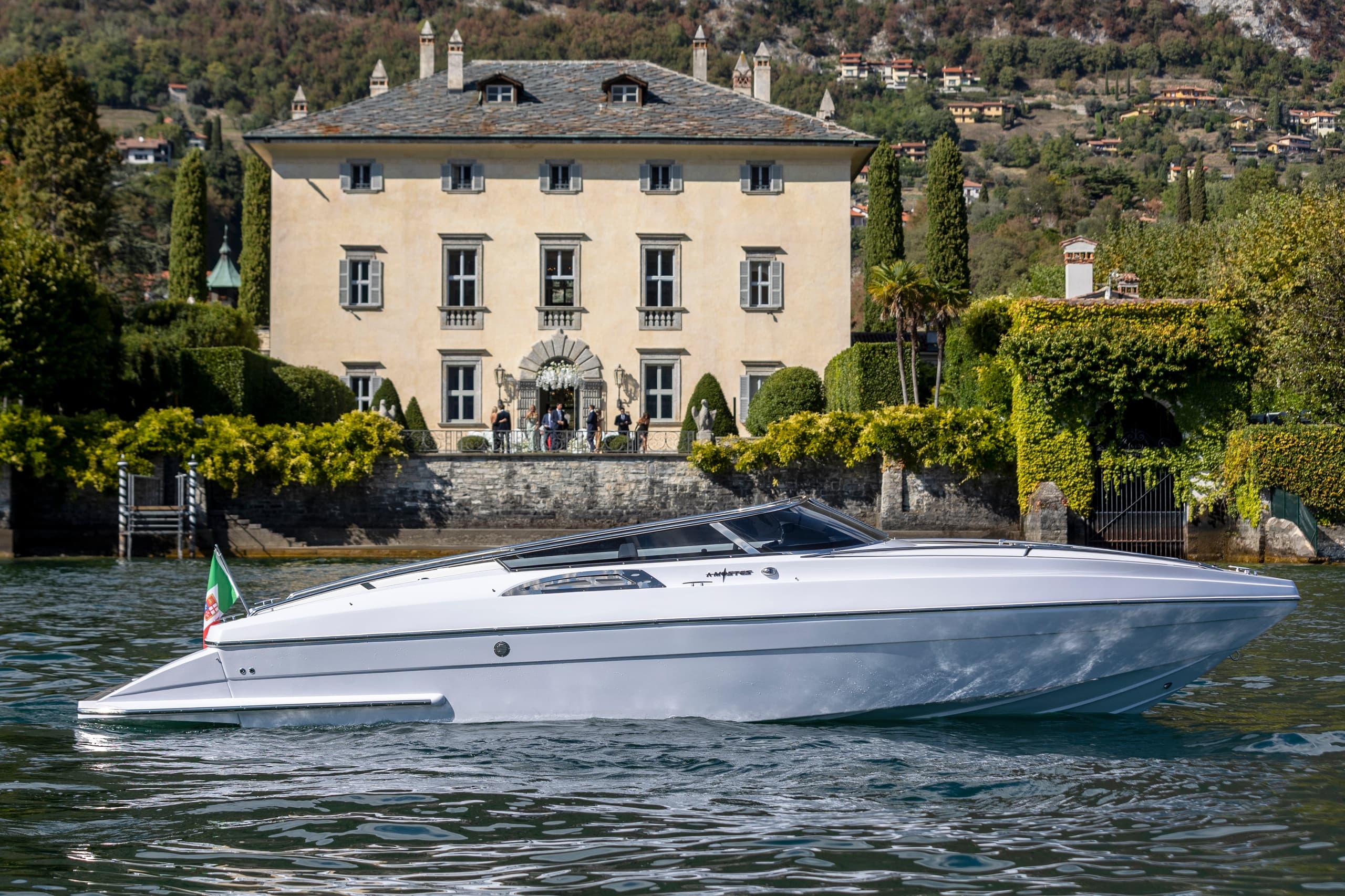 Sleek boat passing a grand lakeside villa on calm Lake Como