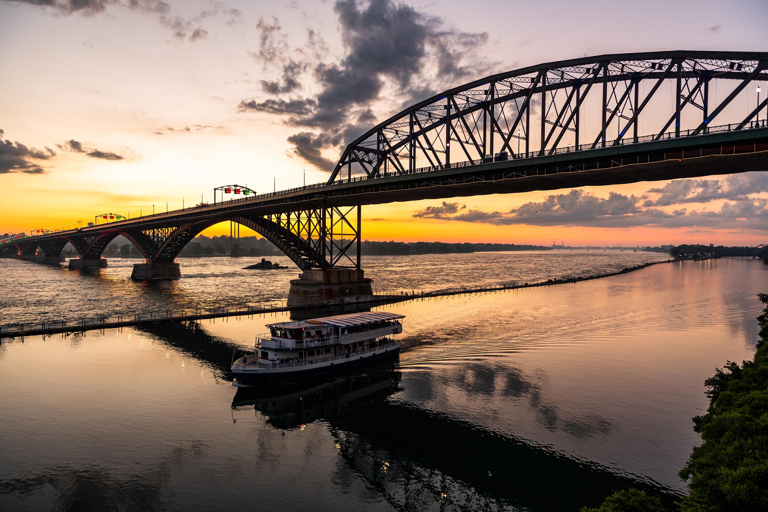 Passenger cruise boat passing under sunset bridge at harbor
