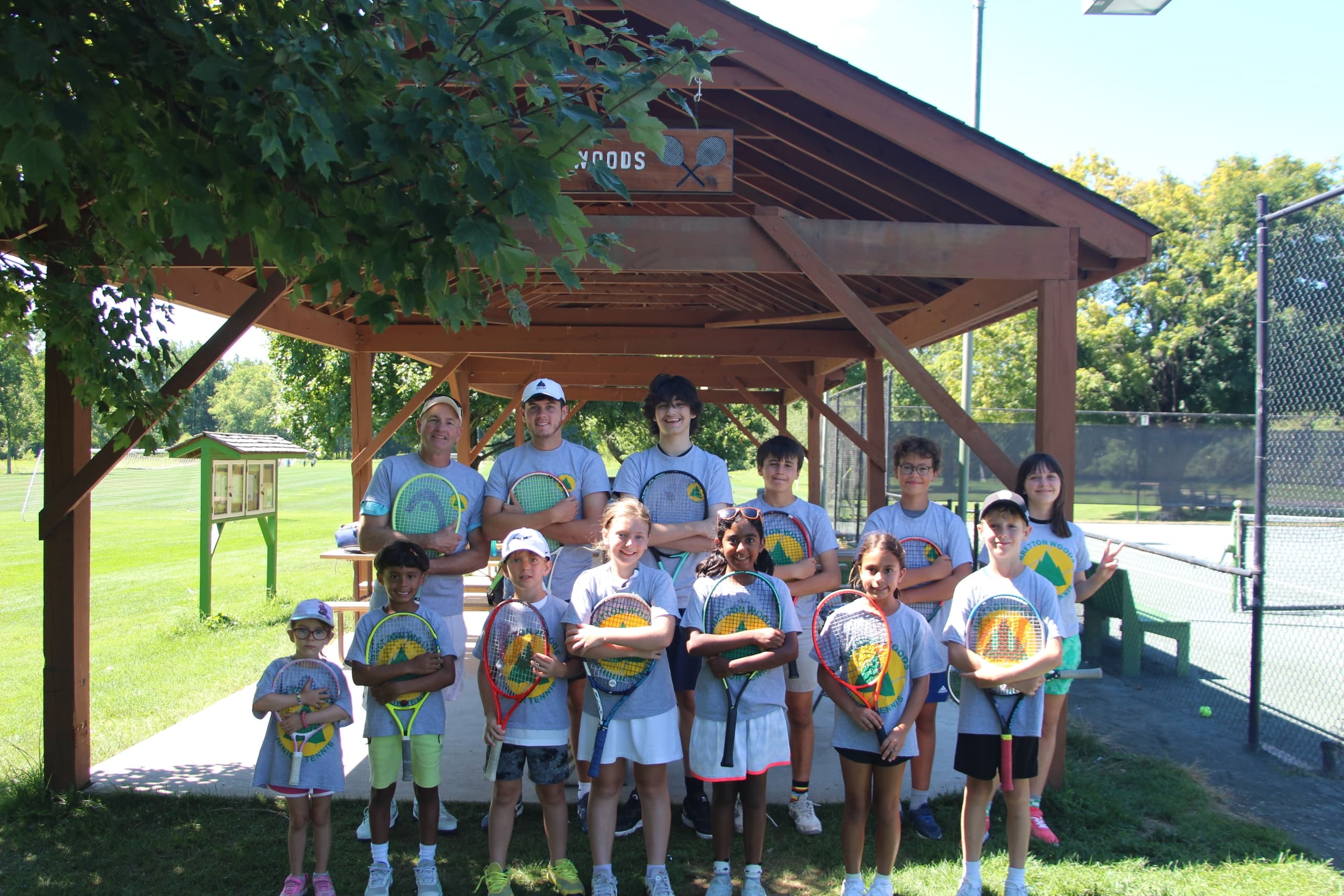 Junior tennis players under pavilion at outdoor tennis camp