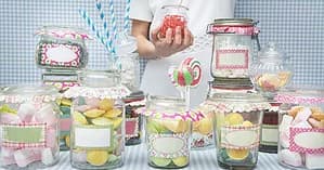 Colorful candy jars arranged on striped tablecloth at indoor dessert station