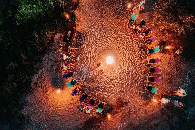 Aerial view of beach bonfire circle with chairs at dusk