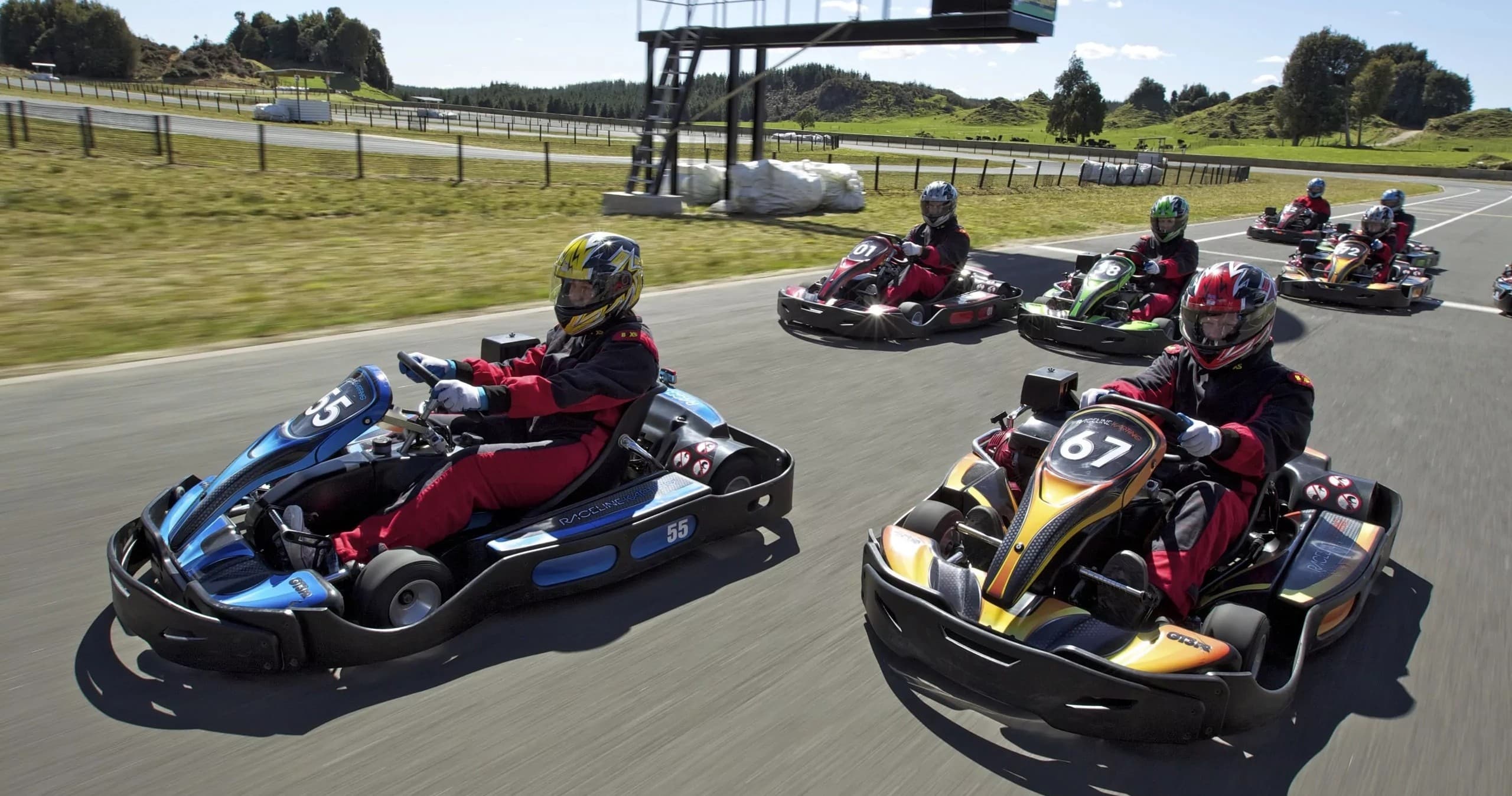 Multiple go-kart drivers racing competitively on paved outdoor circuit