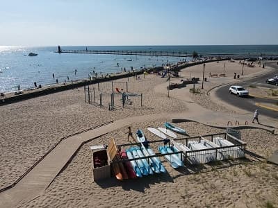 Aerial beach view with stacked kayaks near pier on coastline