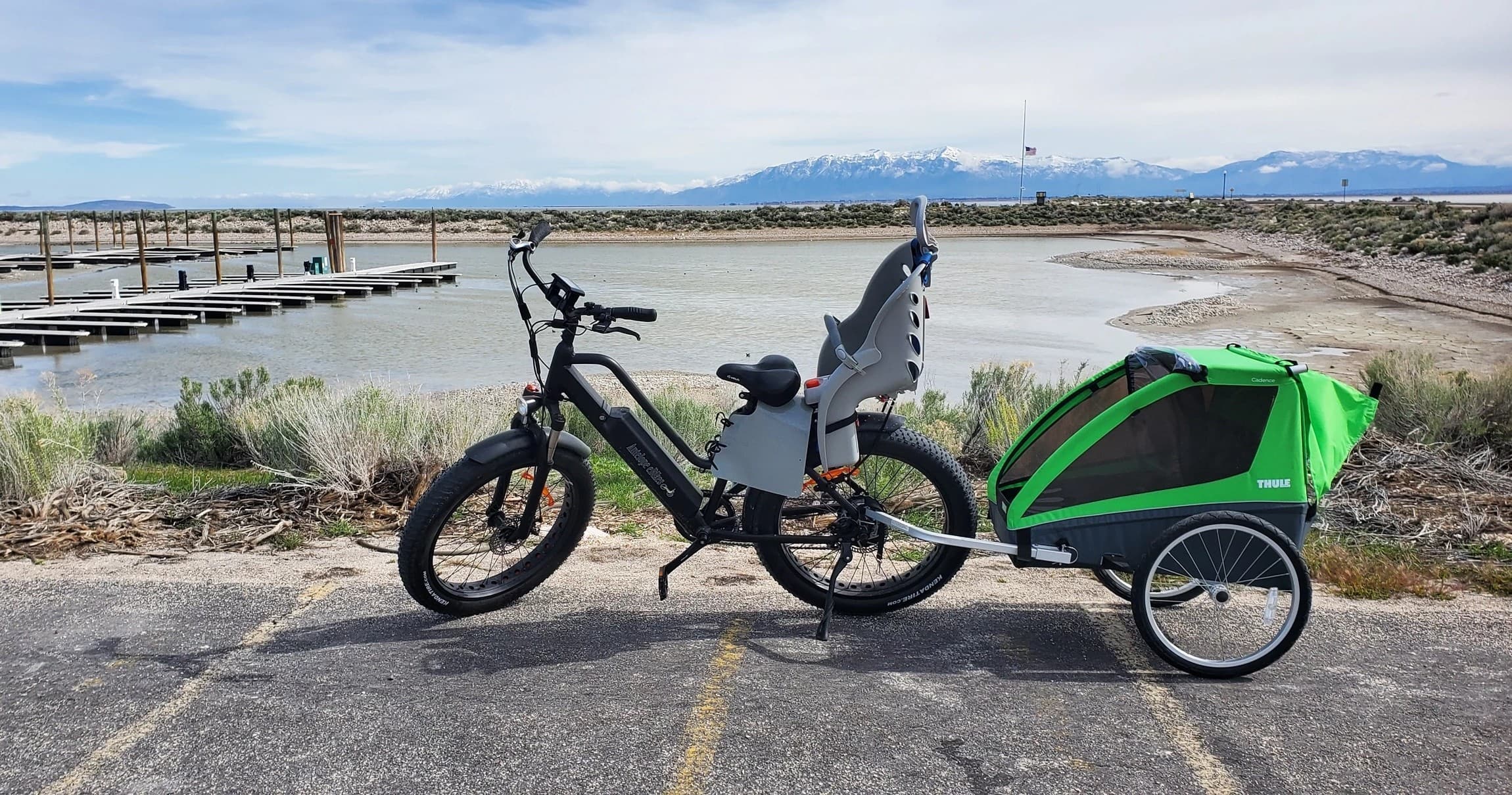 E-bike with child trailer parked by shoreline for coastal touring