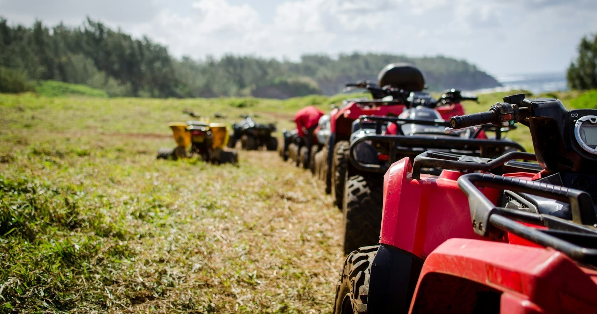 ATVs lined up on coastal grassy trail for guided eco tour