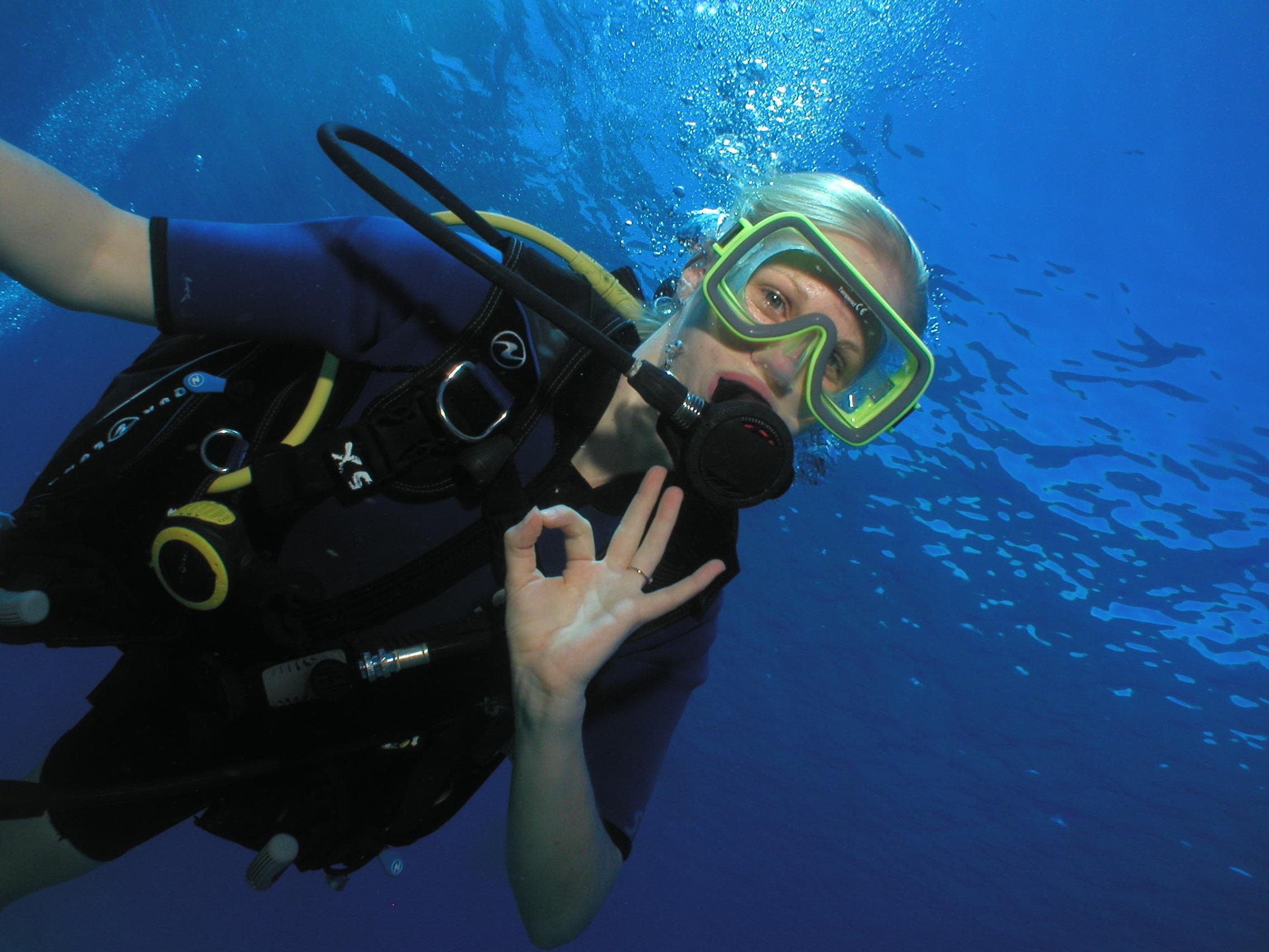 Scuba diver giving OK sign in clear Maui ocean blue waters