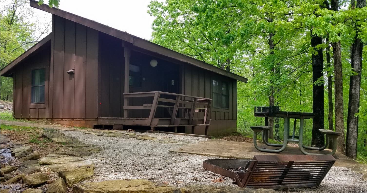 Brown cabin porch with picnic bench, relaxing woods retreat stay