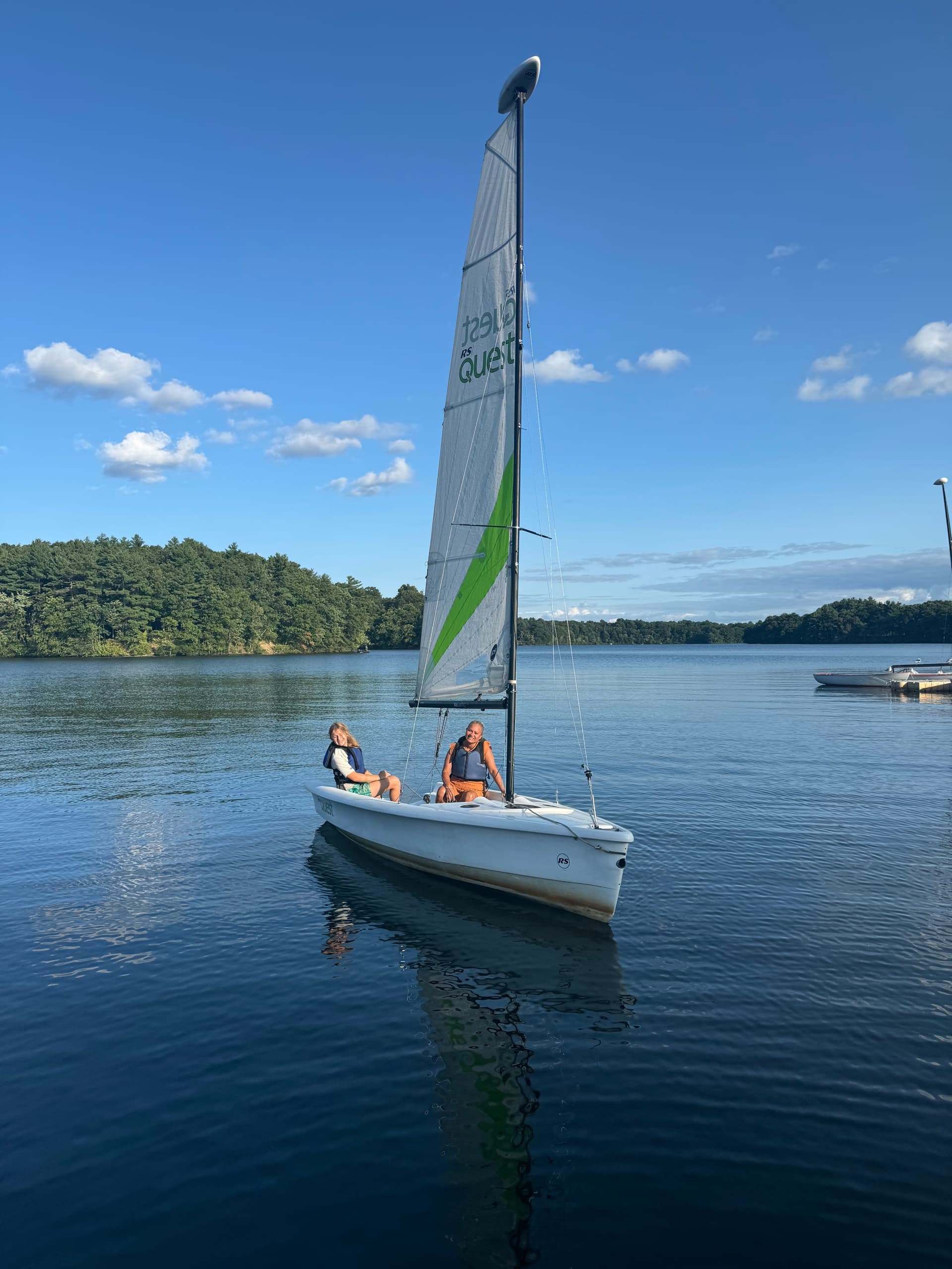 Small sailboat cruising on tranquil lake under blue sky