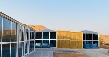 Modern glass desert cabins overlooking sandy dunes at sunrise